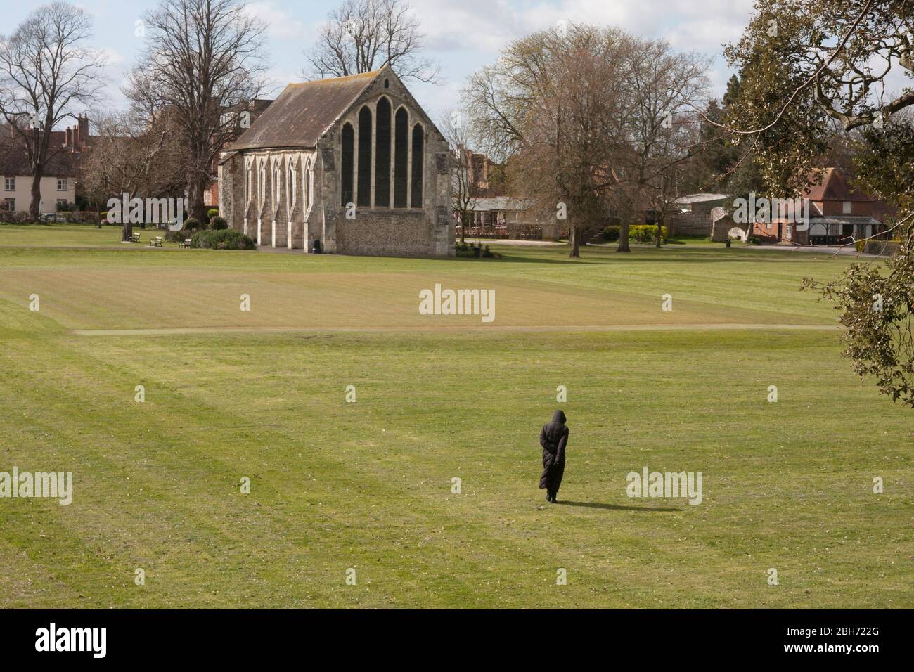 lone pedestrian in deserted Priory Park, Chichester, West Sussex, during coronavirus lockdown, March 2020 Stock Photo