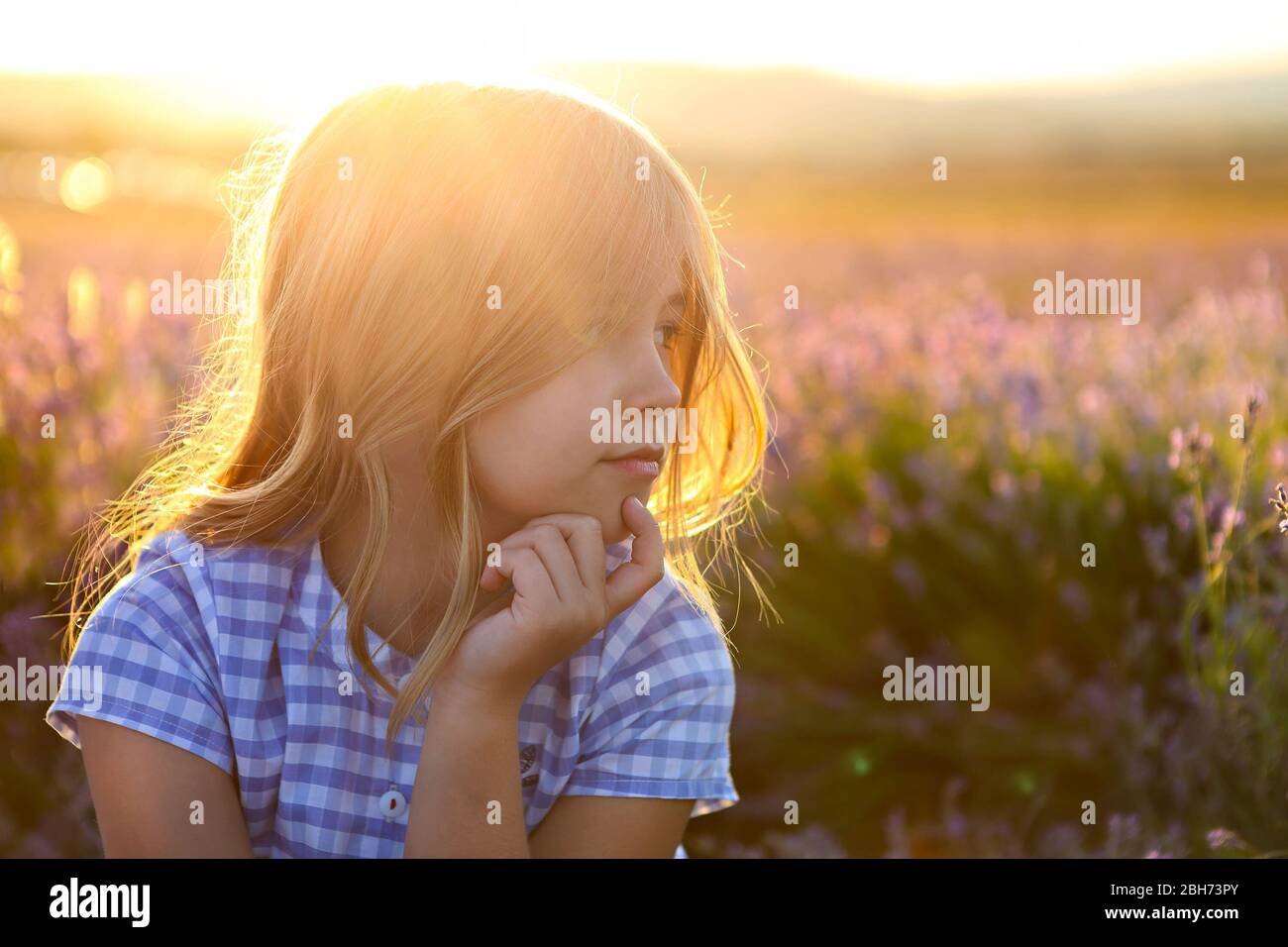 Portrait of the happy little girl blonde with long hair at sunset in ...