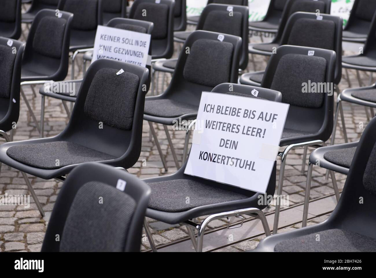 Dresden, Germany. 24th Apr, 2020. A sign with the inscription "I remain  empty until further notice! Your concert chair" is written on an empty chair  in the Altmarkt. With orphaned chairs in