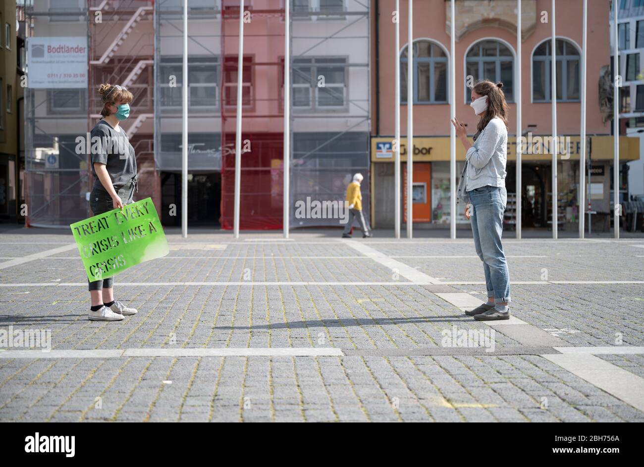 Stuttgart, Germany. 24th Apr, 2020. Two activists of the climate movement "Fridays for Future" talk to each other during an action on the market place. Nationwide and also in Baden-Württemberg, the organisation called for painted posters to be put up on windows and in the cities, thus continuing the protest in compliance with contact restrictions. Credit: Marijan Murat/dpa/Alamy Live News Stock Photo