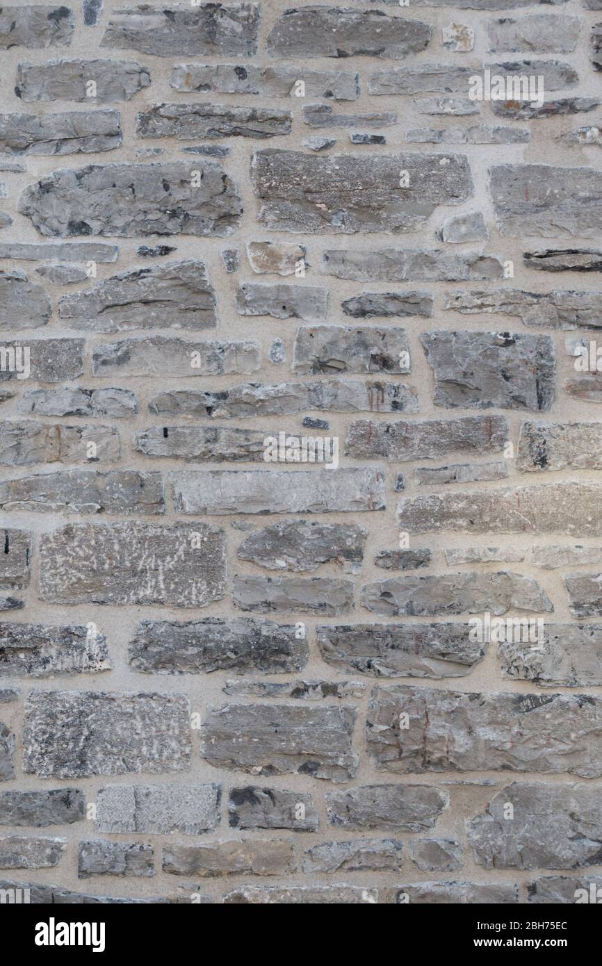 Textured natural wallpaper of hammered chiseled granite stone wall and grout in sunshine Stock Photo