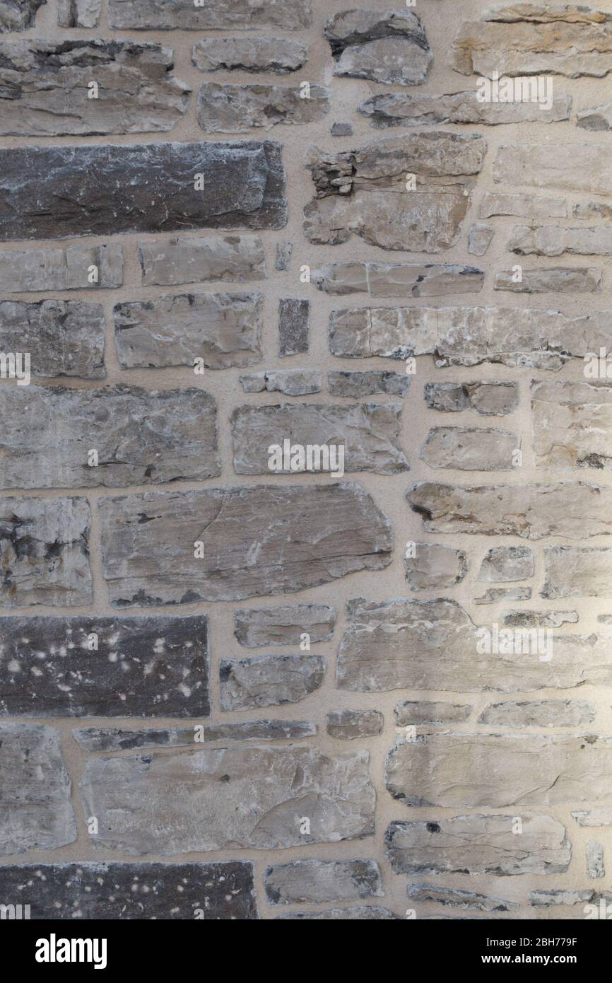 Textured natural wallpaper of hammered chiseled granite stone wall and grout in sunshine Stock Photo
