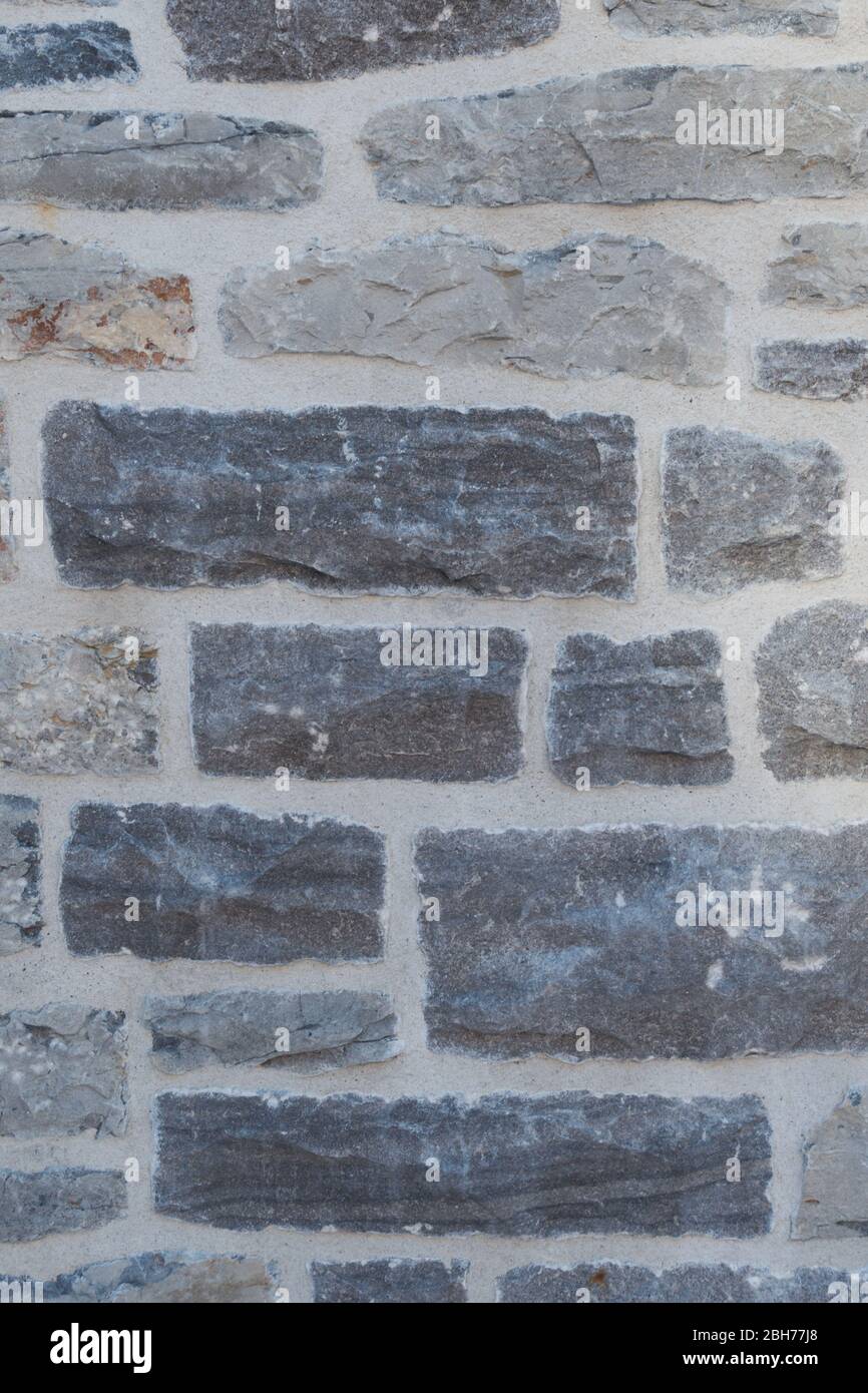 Textured natural wallpaper of hammered chiseled granite stone wall and grout in sunshine Stock Photo