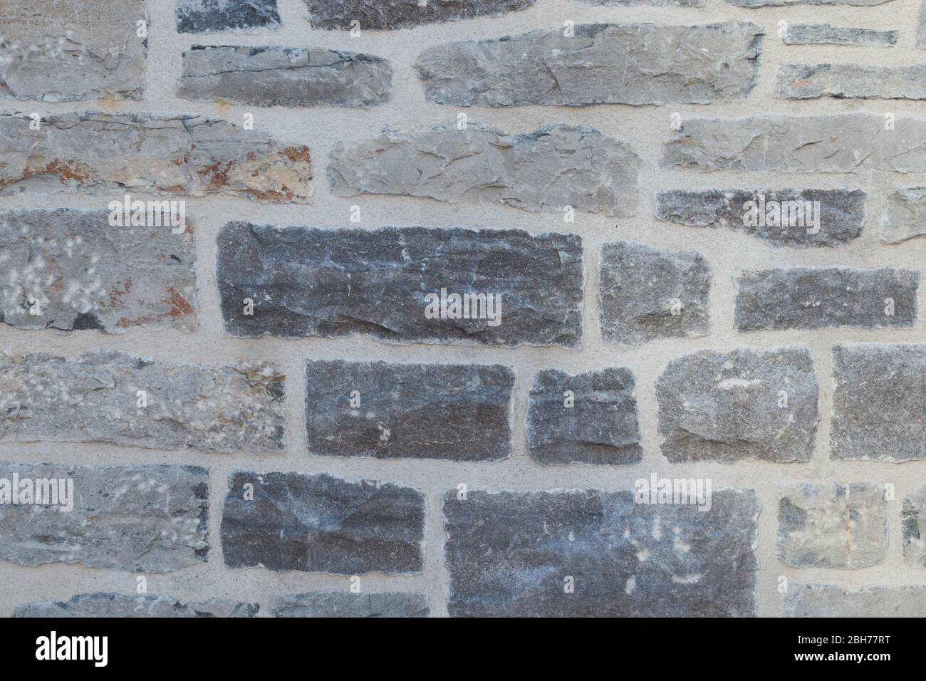 Textured natural wallpaper of hammered chiseled granite stone wall and grout in sunshine Stock Photo