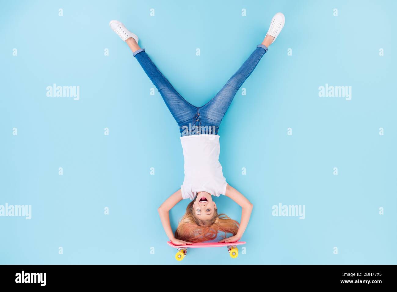 Top above high angle view full body photo of positive girl sporty kid ride longboard upside down show tongue out wear white clothes lay isolated over Stock Photo