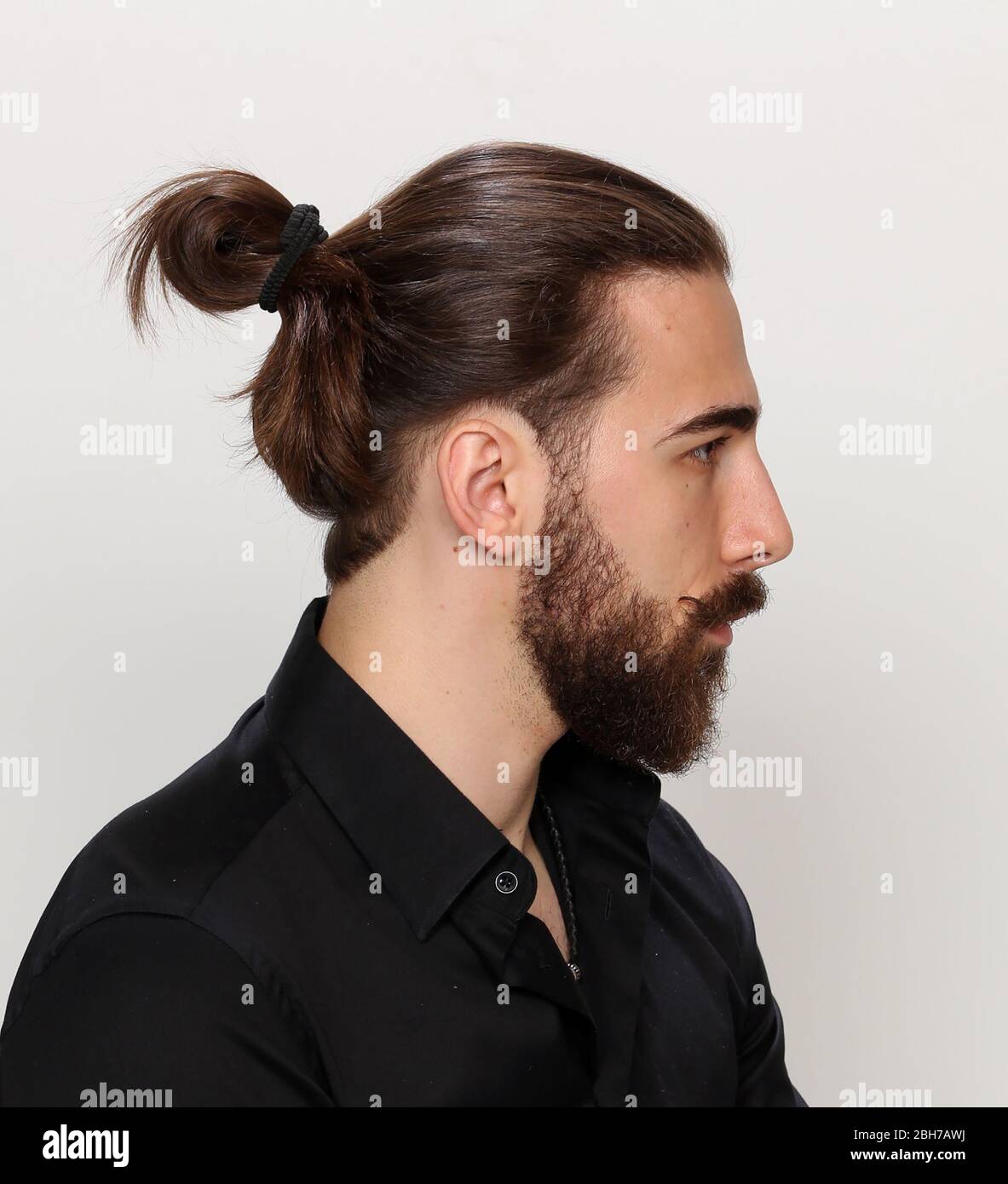Young, fashionable male model with long hair and beard posing in studio ...