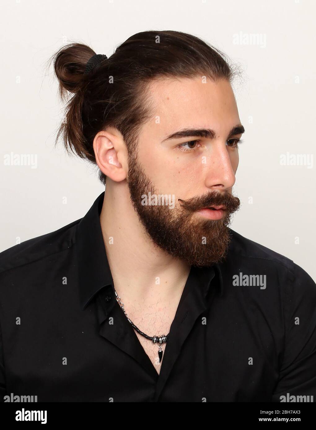 Young, fashionable male model with long hair and beard posing in
