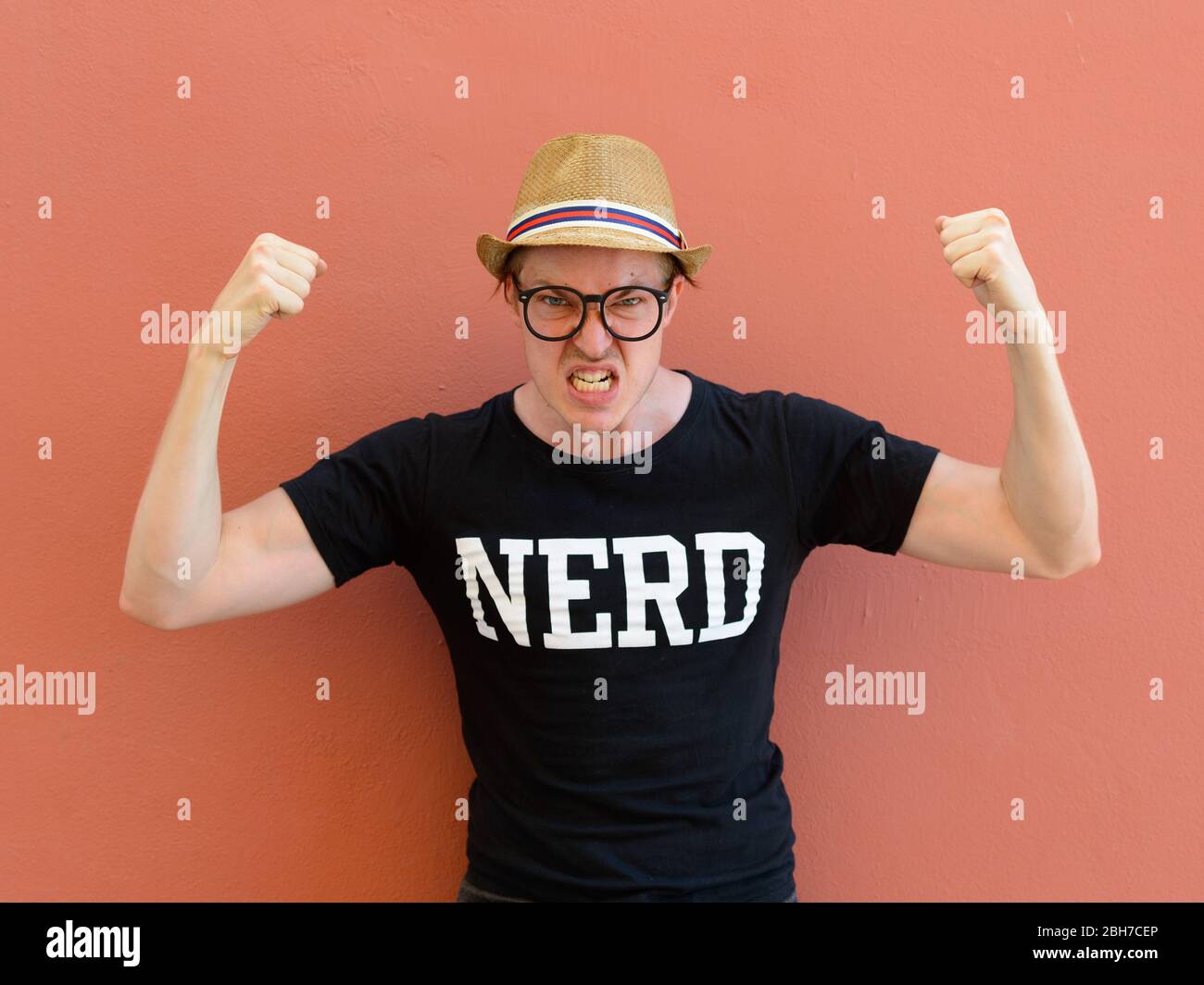 Young nerd tourist man flexing both arms Stock Photo