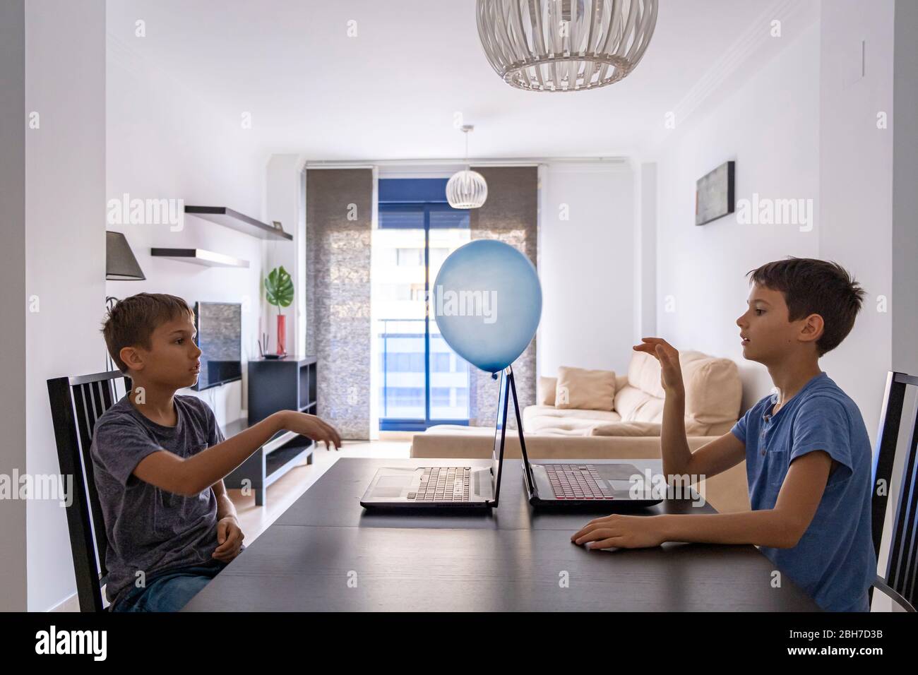 Children learning with laptop computer and play with balloon at home. Technology, education, online distance learning for kids Stock Photo