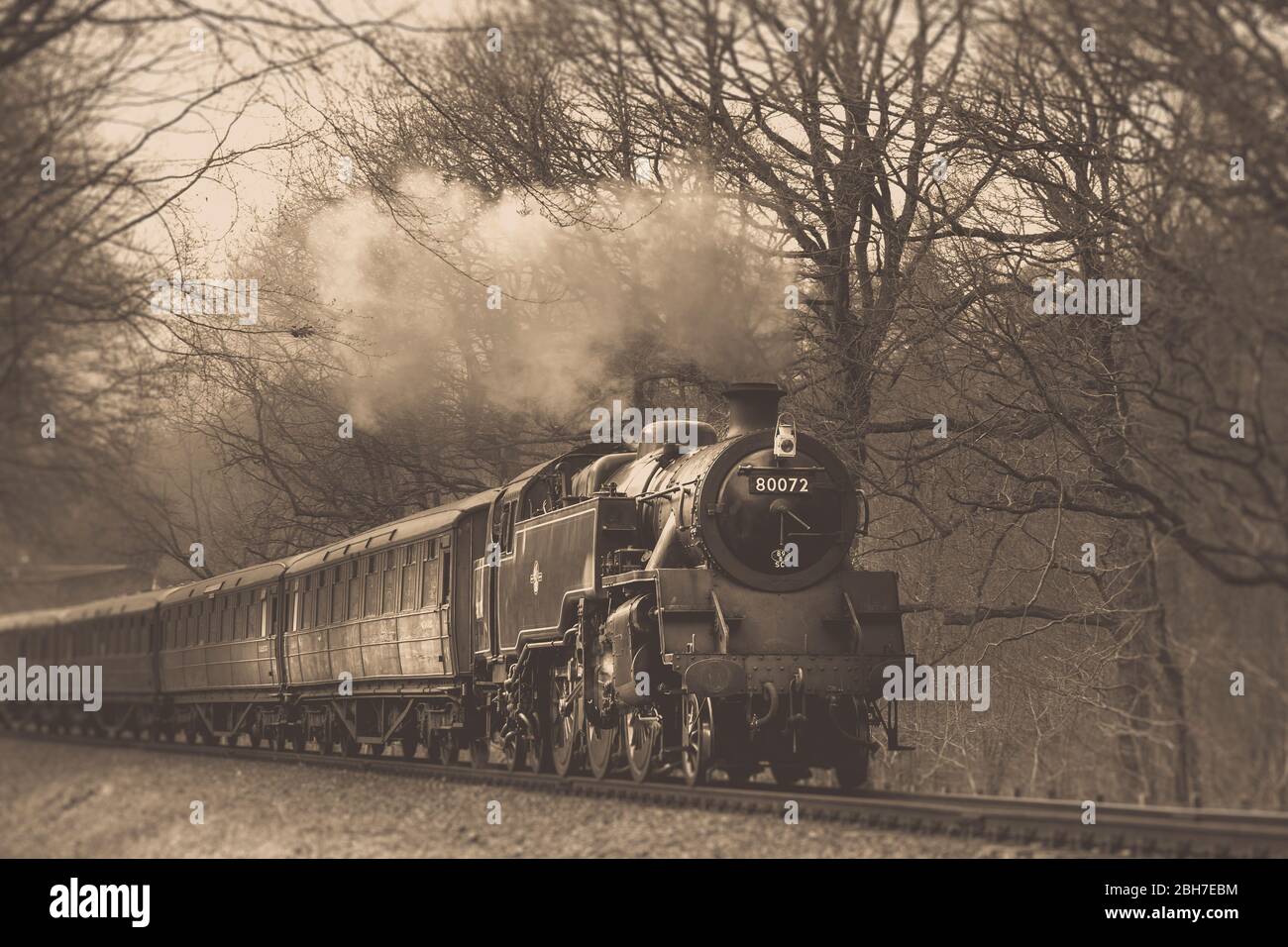 Low angle, sepia view of vintage UK steam train oncoming on railway track in Worcestershire rural countryside, Severn Valley Railway heritage line, UK. Stock Photo