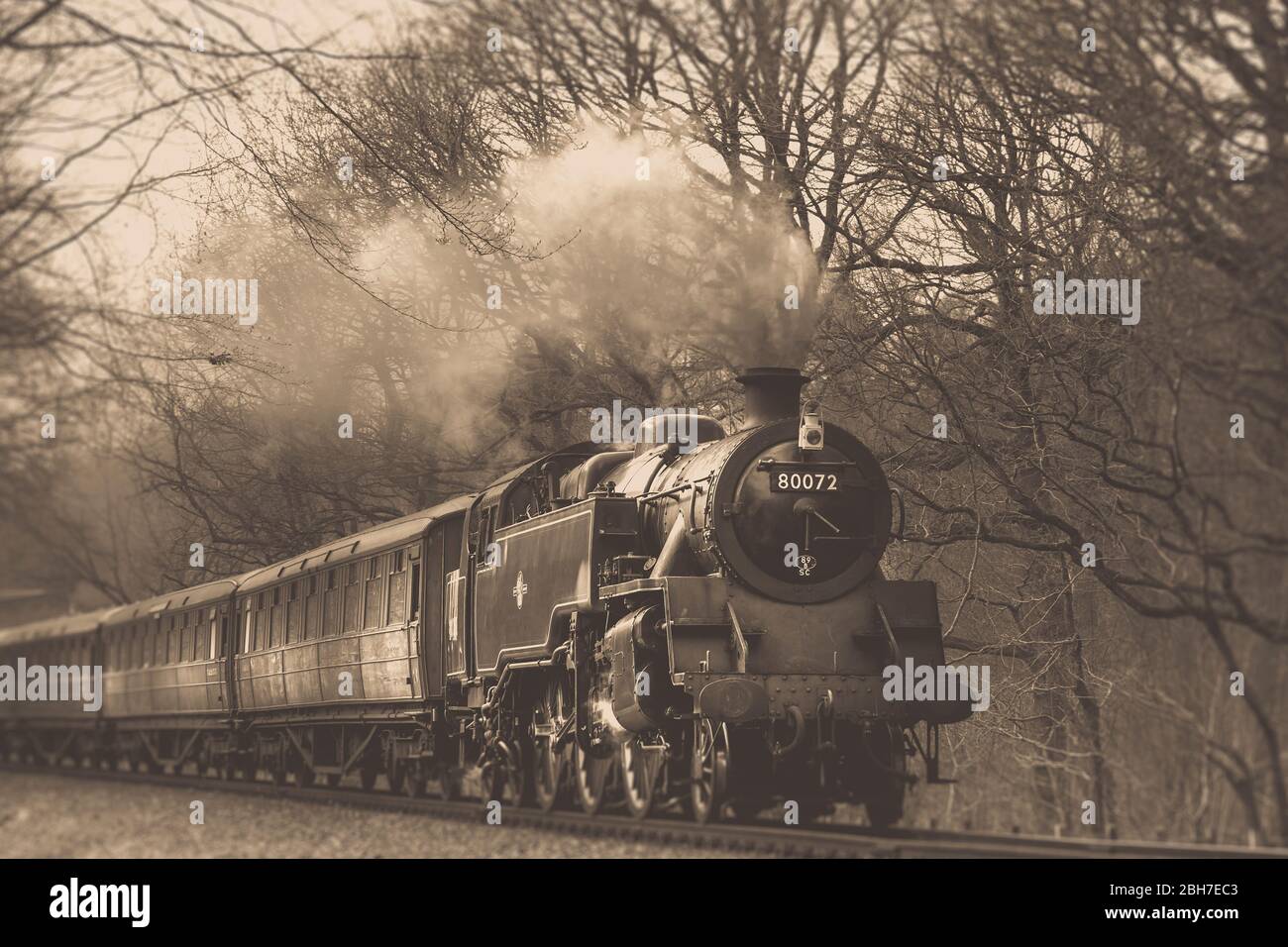 Low angle, sepia view of vintage UK steam train oncoming on railway track in Worcestershire rural countryside, Severn Valley Railway heritage line, UK Stock Photo