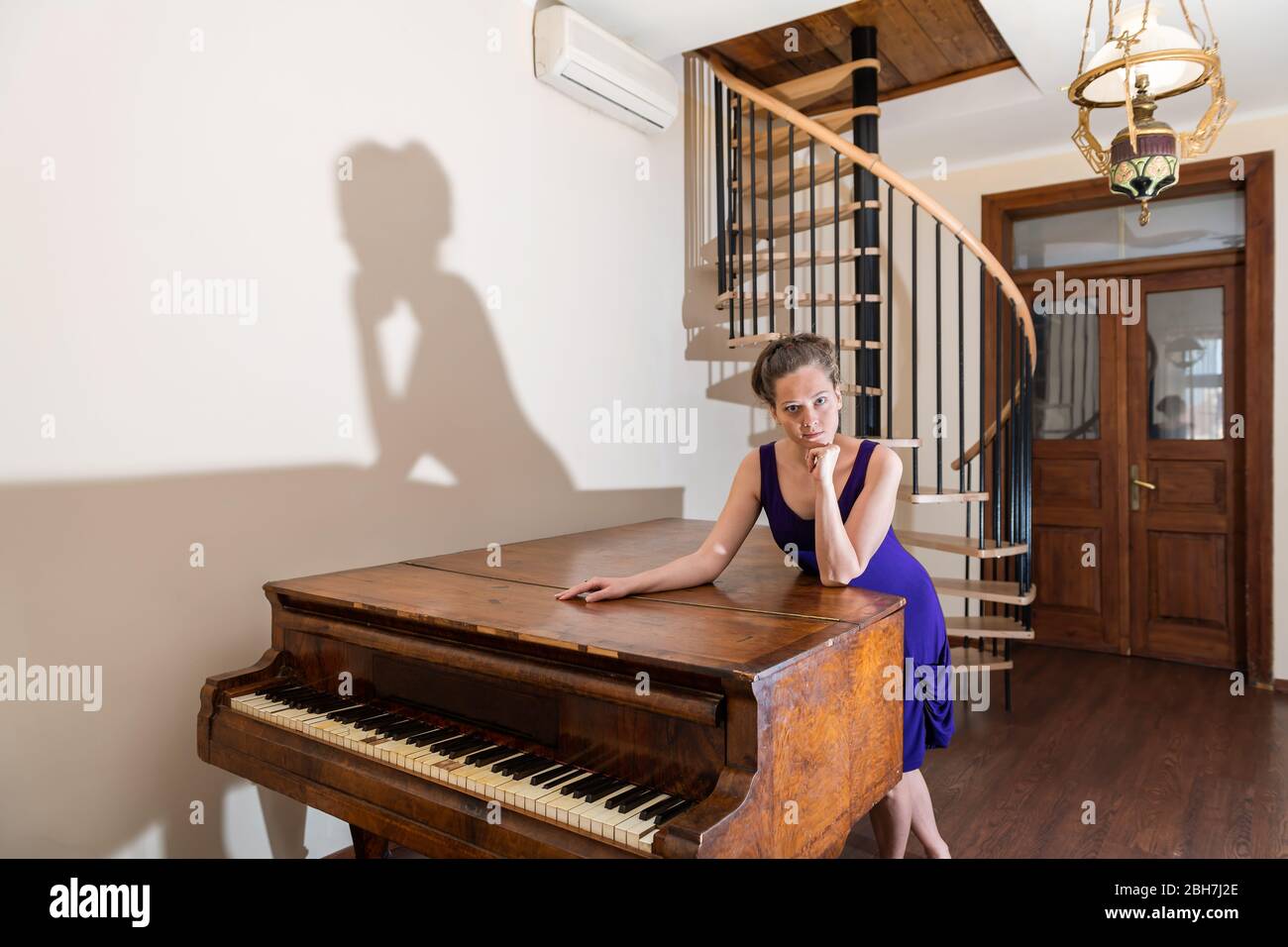 Wooden old-fashioned forte piano with young girl woman pianist looking ...