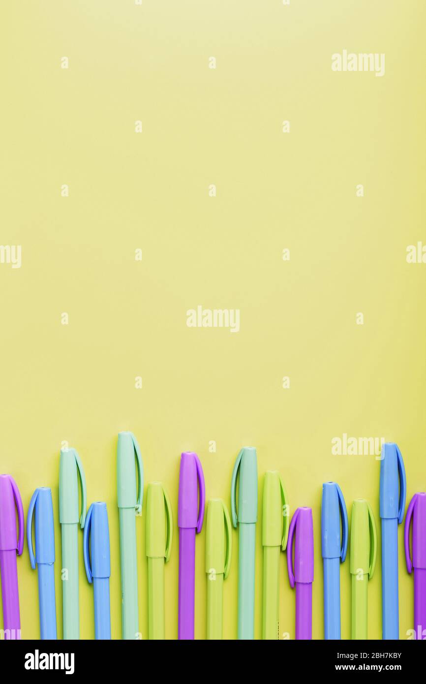 Multi-colored pens on a yellow background with free space. Stock Photo