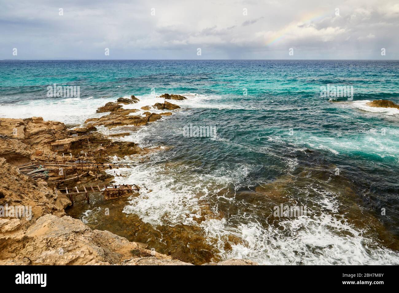 Traditional boathouses called escars in Es Carnatge coastline with blue rough waters (Formentera, Pityuses, Balearic Islands, Mediterranean sea,Spain) Stock Photo