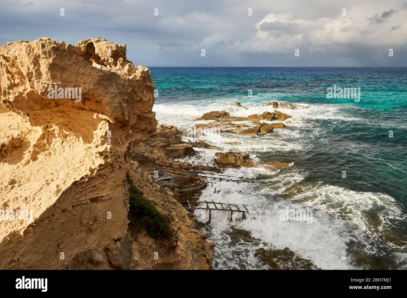 Traditional boathouses called escars in Es Carnatge coastline with blue rough waters (Formentera, Pityuses, Balearic Islands, Mediterranean sea,Spain) Stock Photo