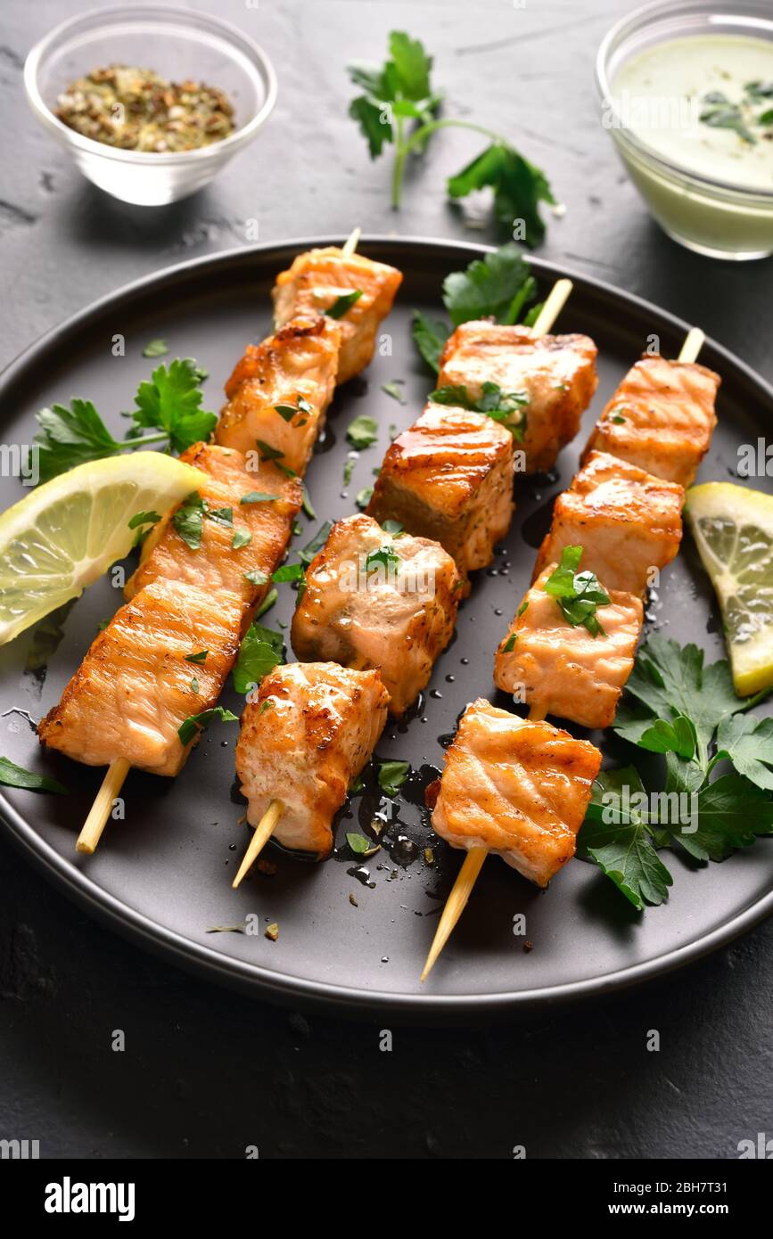 Grilled salmon kebab. Barbecue salmon skewers on black stone background  Stock Photo - Alamy