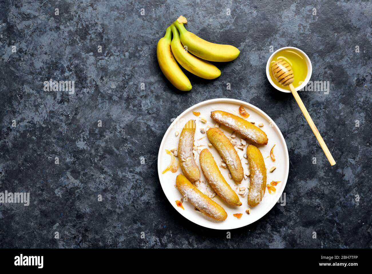 Deep fried bananas on white plate over blue stone background with free