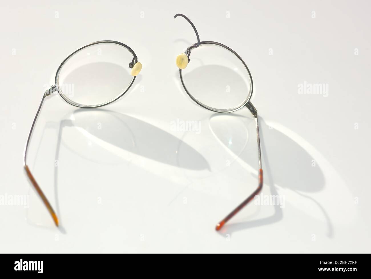 A pair of Titanium Wire Rim eye glasses that have broken and split apart on the nose bridge section. Stock Photo