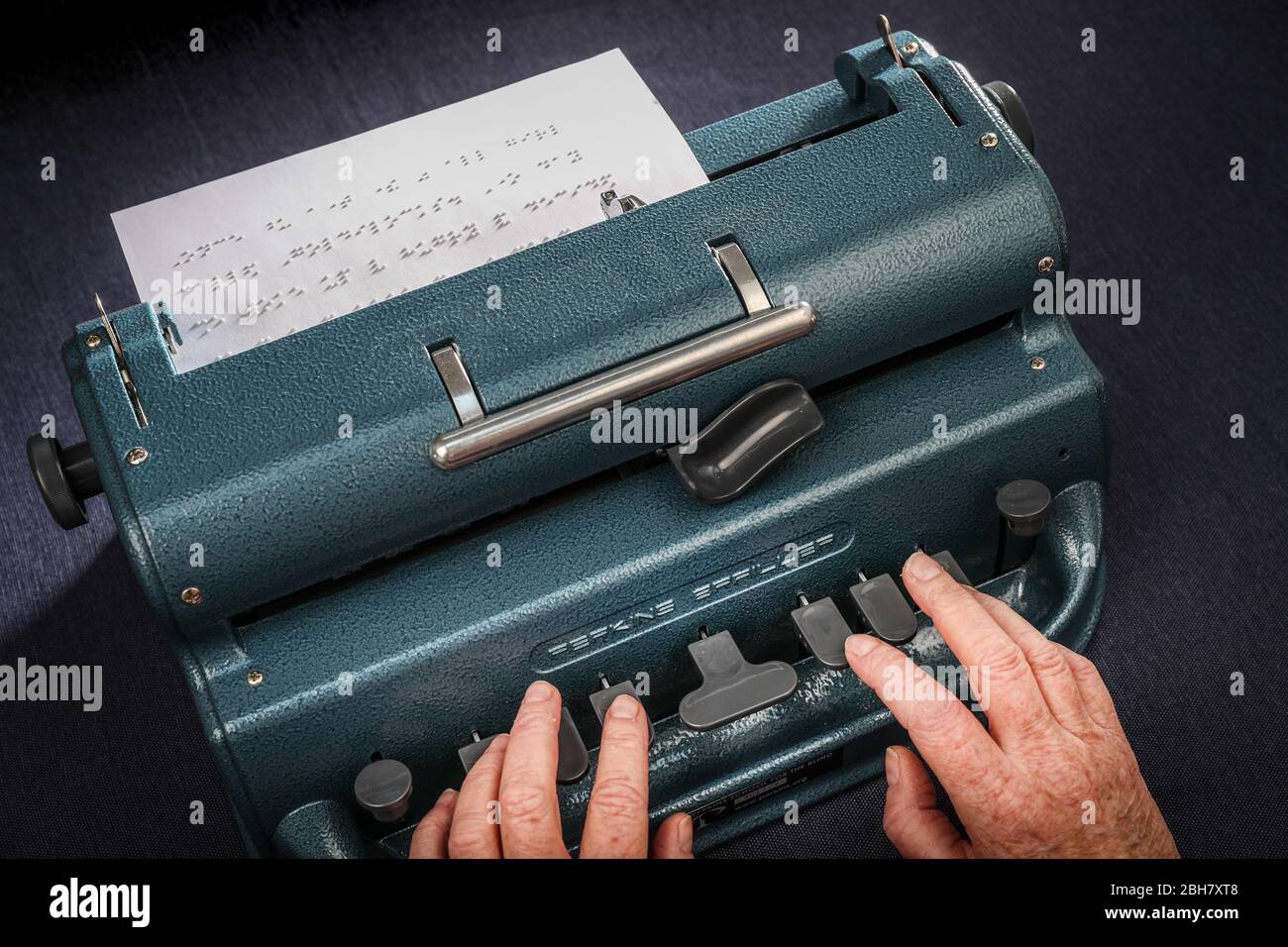 A woman typing in braille using a Perkins Brailler typewriter. Stock Photo