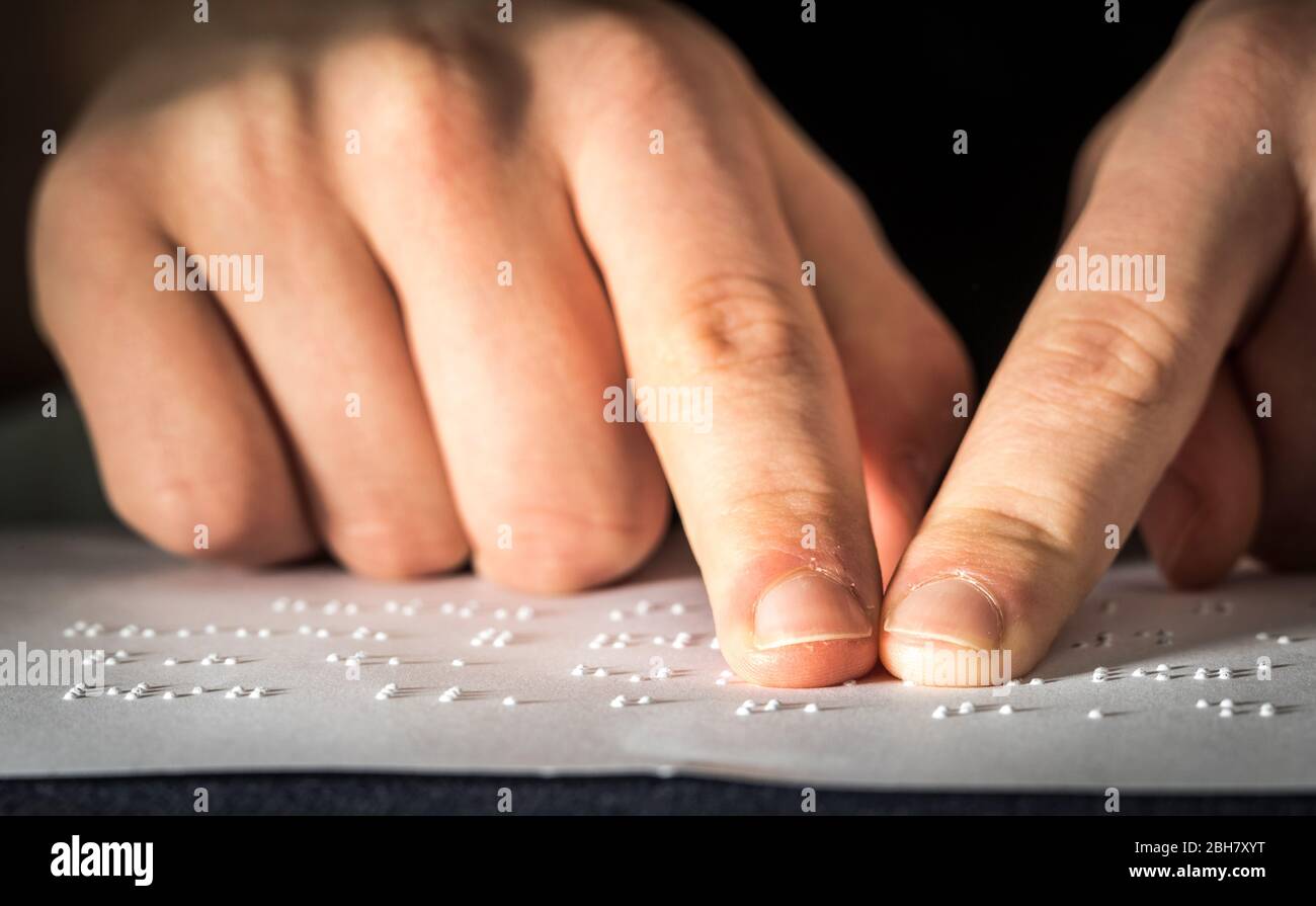 A teenage school pupil reading braille text with his fingers Stock Photo