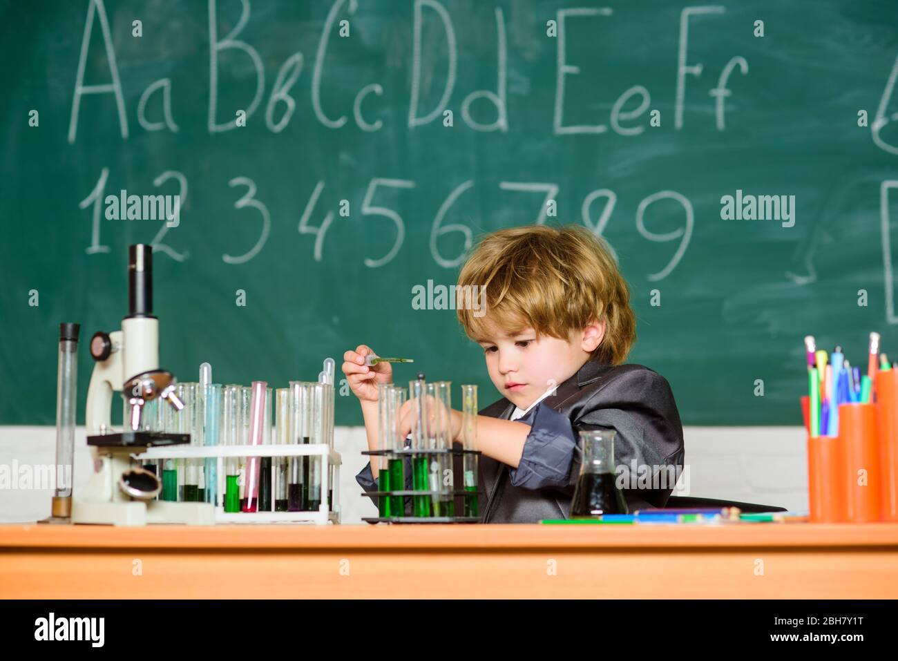 Educational experiment. Boy microscope and test tubes school classroom