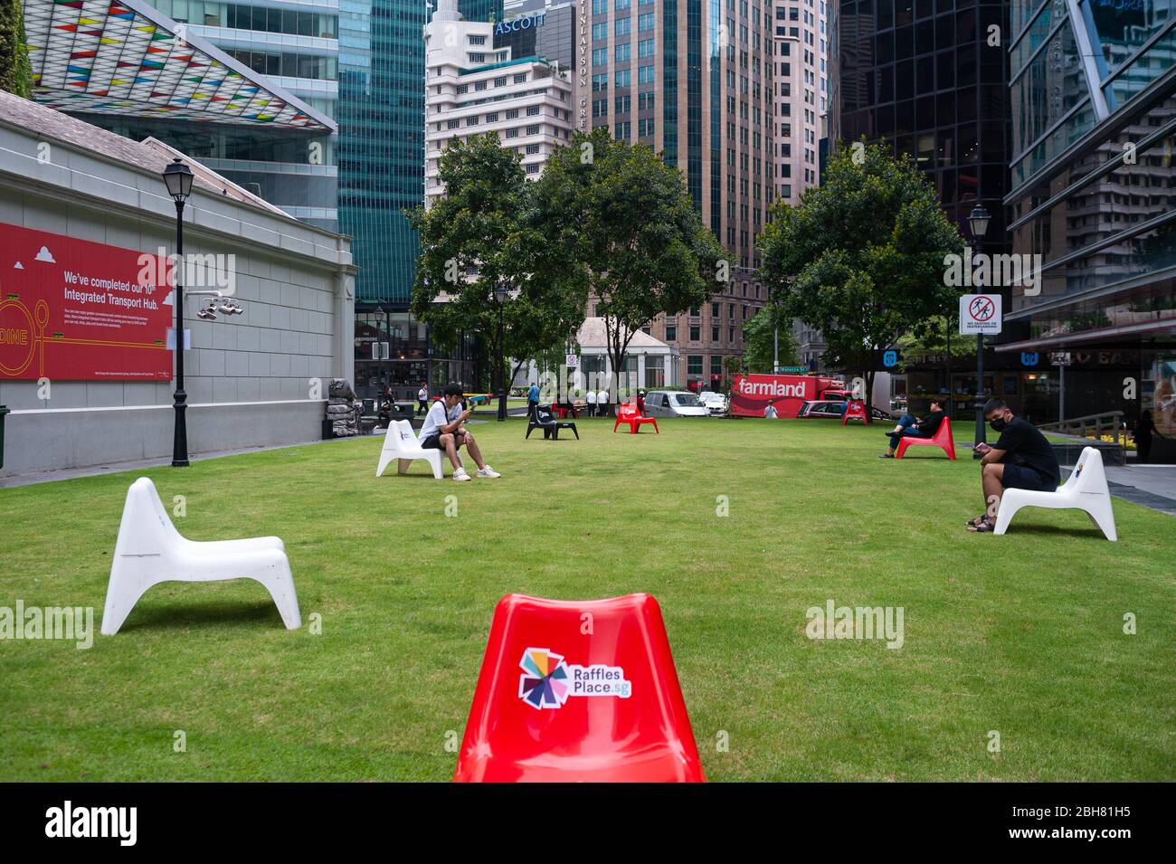 02.04.2020, Singapore, , Singapore - In the business district at Raffles Place, people sit spatially separated from each other on plastic chairs to pr Stock Photo