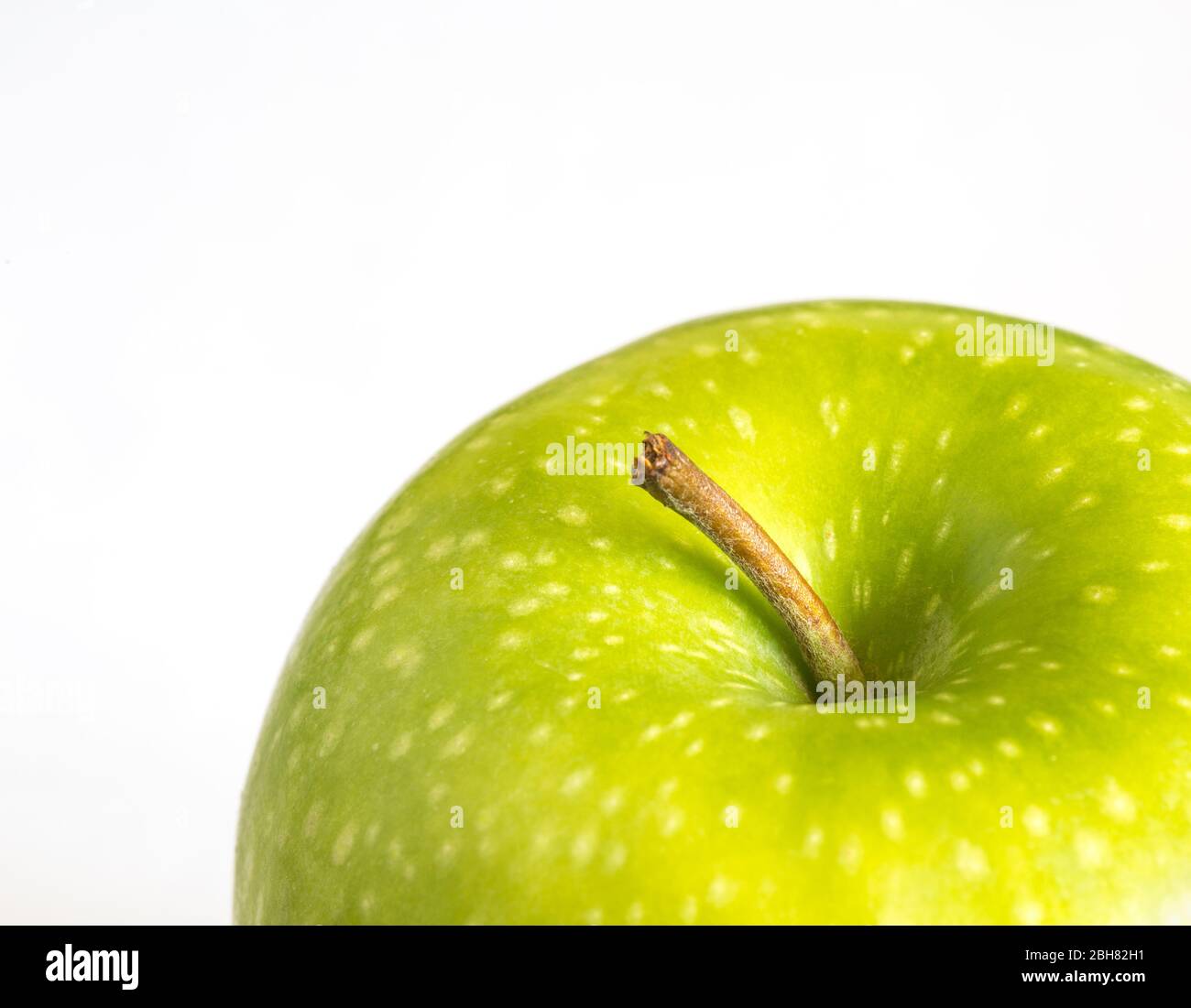 A close up of an organic green apple on a white background showing the