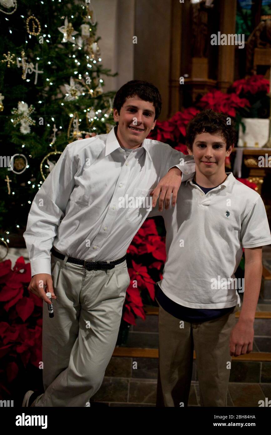 Austin Texas USA, December 24, 2009: Brothers, age 15 and 13, stand by a Christmas tree in a Lutheran church after Christmas Eve service. MR © Bob Daemmrich Stock Photo
