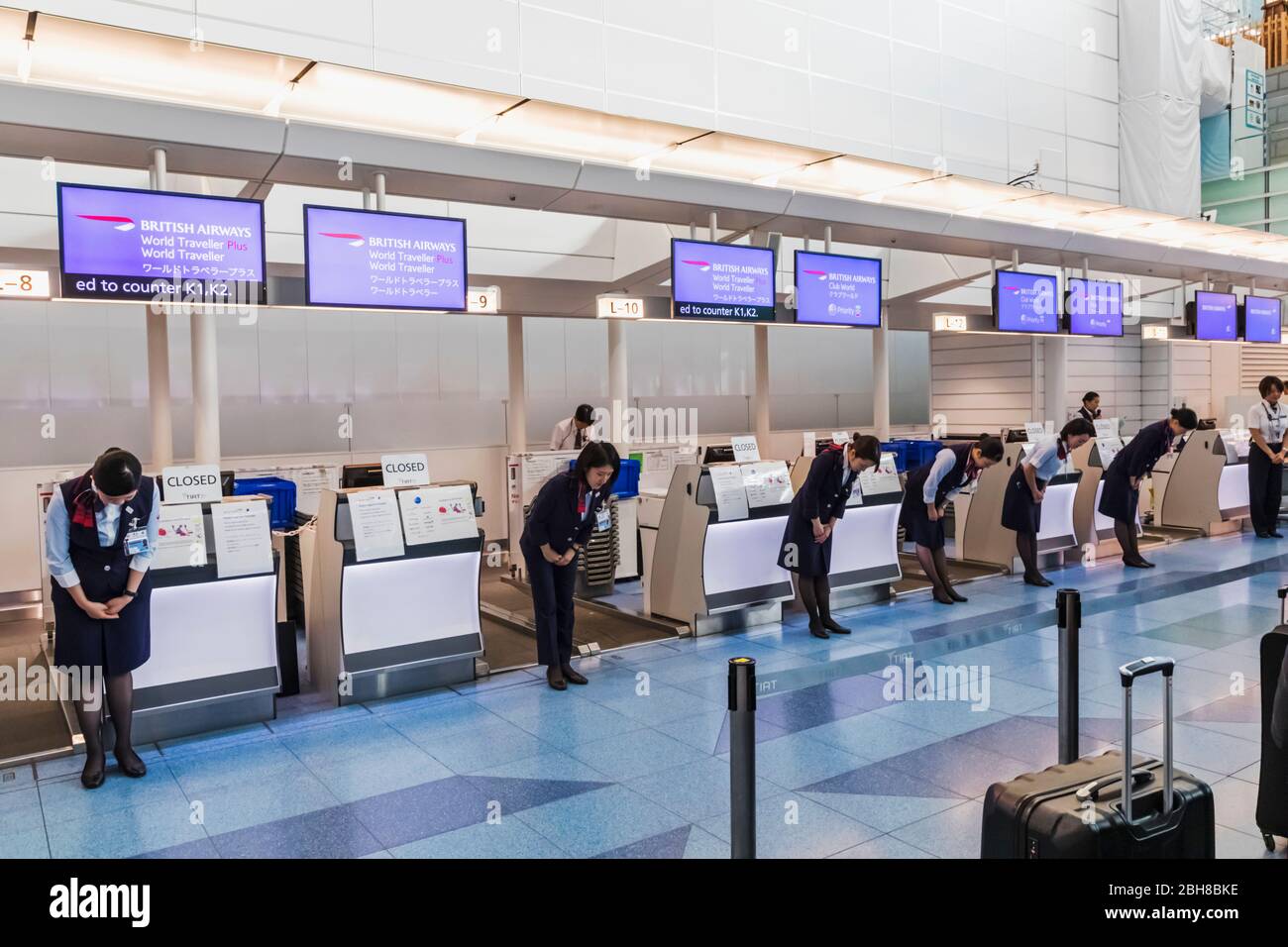 Japan, Honshu, Tokyo, Haneda Airport, International Terminal, Departure Area, British Airways Staff Bowing to Customers Prior to Opening Check-in Counters Stock Photo