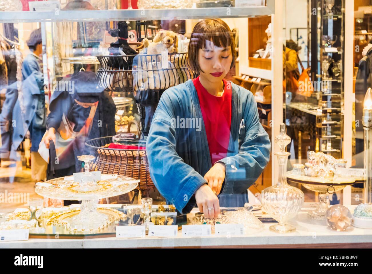 Japan, Honshu, Tokyo, Marunouchi, Nakadori Street, Brick Square, Sales Girl Arranging Window Display of Products Stock Photo