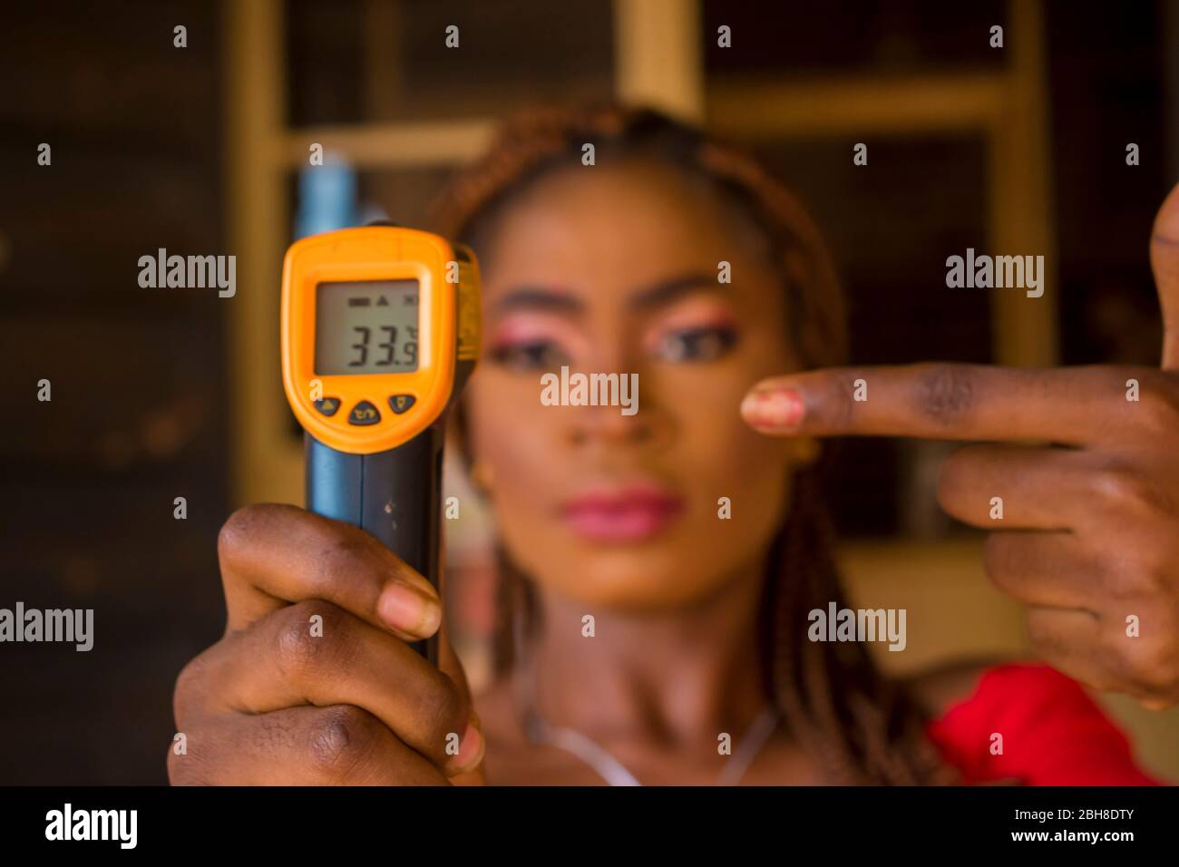 Close-up shot of a young african woman holding infrared forehead ...