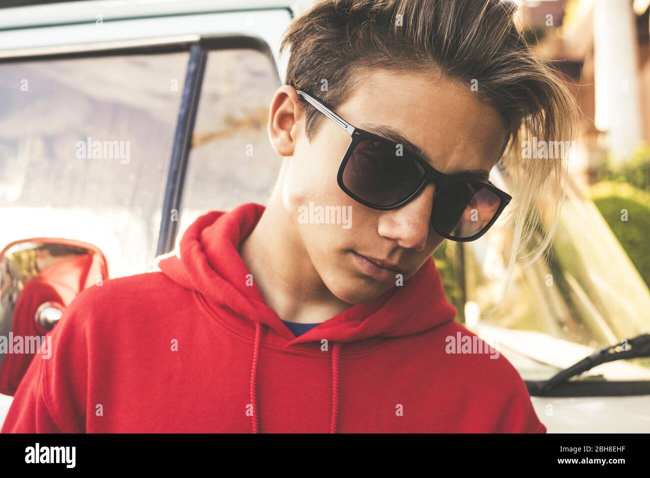 beautiful boy model young age pose outdoor with black sunglasses - trendy millennial kid 15 years old - vintage brown tones colors image fashion concept Stock Photo
