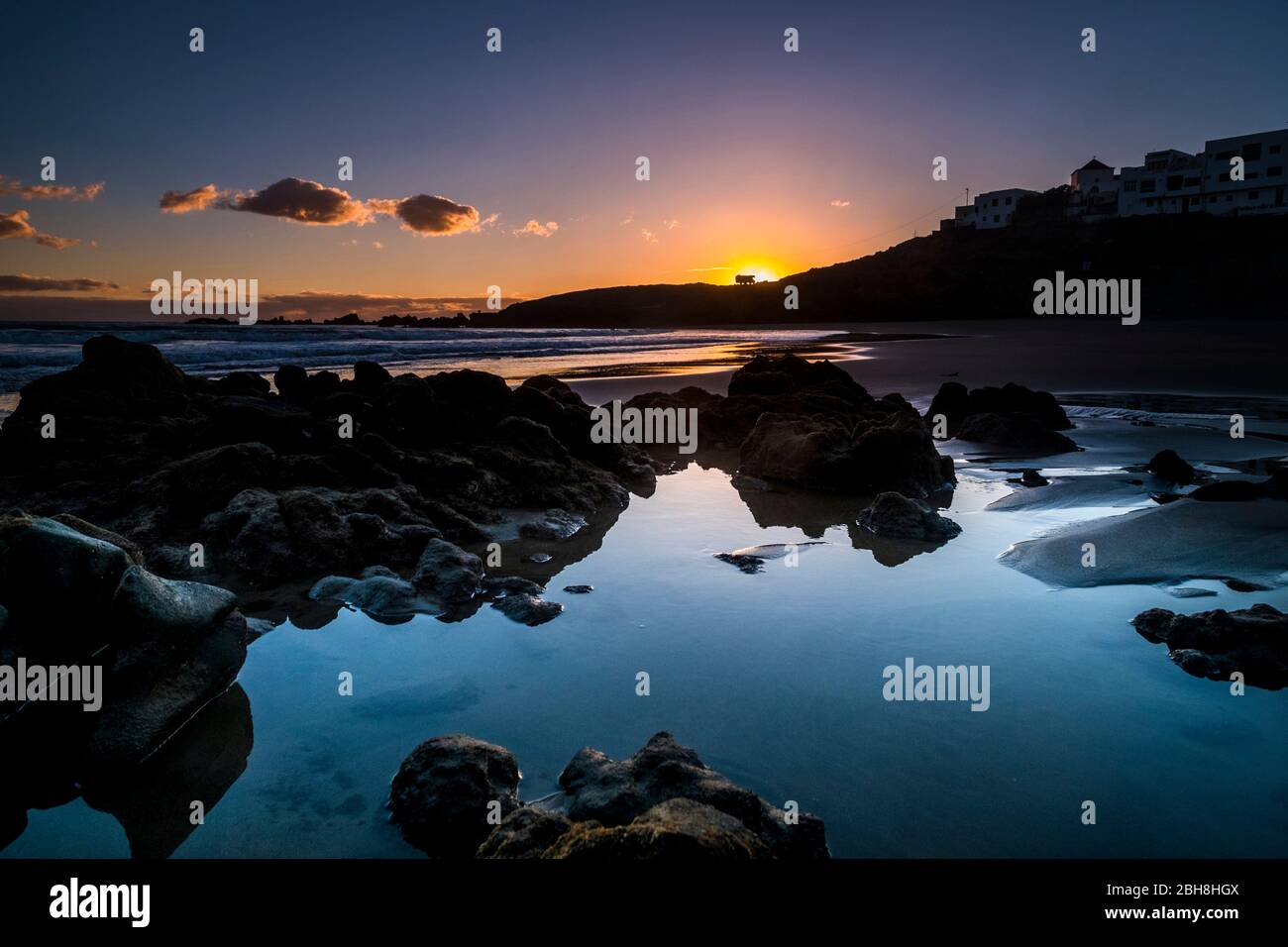 Sunrise or sunset at the ocean beach - beautiful colors and wave and sky - environment and vacation scenery place concept - landscape with coastal city and red clouds - magic light before the day Stock Photo
