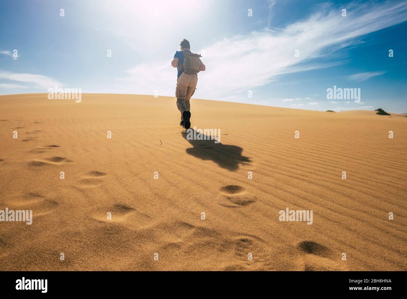 Backpacker people explore and adventure leisure activity concept with man walking on the desert dunes with backpack - alternative vacation for freedom lifestyle - scenic nature outdoor Stock Photo