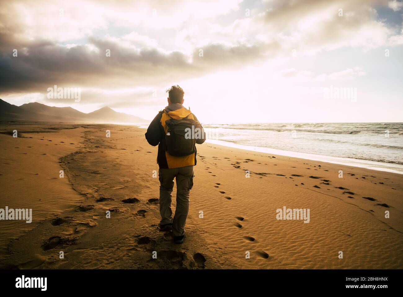 People in back view walking alone with his backpack on the desolation beautiful wild beach for alternative concept of tourism vacation - adventure and explore scenic place - freedom and feeling the nature lifestyle Stock Photo
