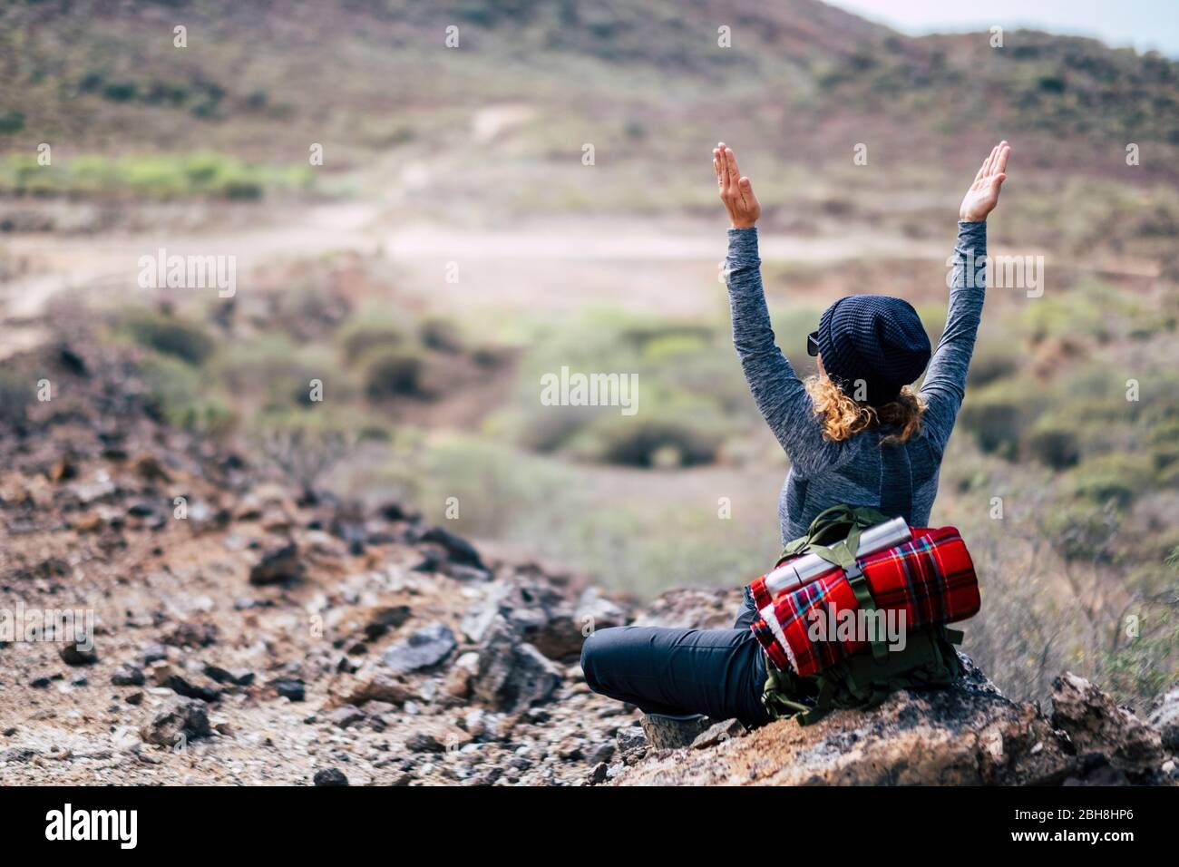 Rear view of woman with blonde curly hair doing yoga position and meditate during travel trekking hiking adventure activity - enjoying and feeling the nature - people healthy lifestyle Stock Photo
