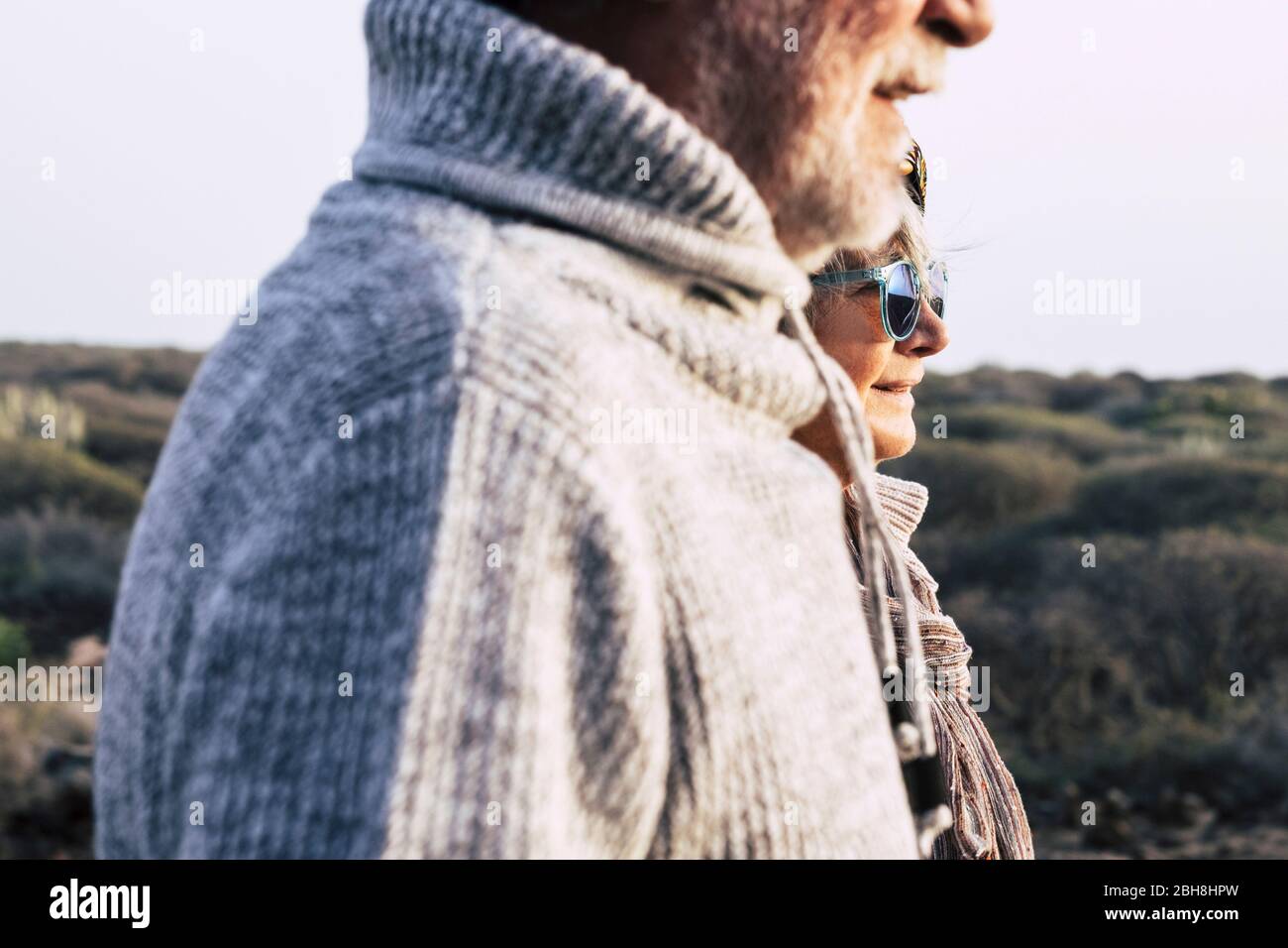 Portrait fashion style mature couple old aged seniors man and woman with nature in background - cold season autumn or spring and sun Stock Photo