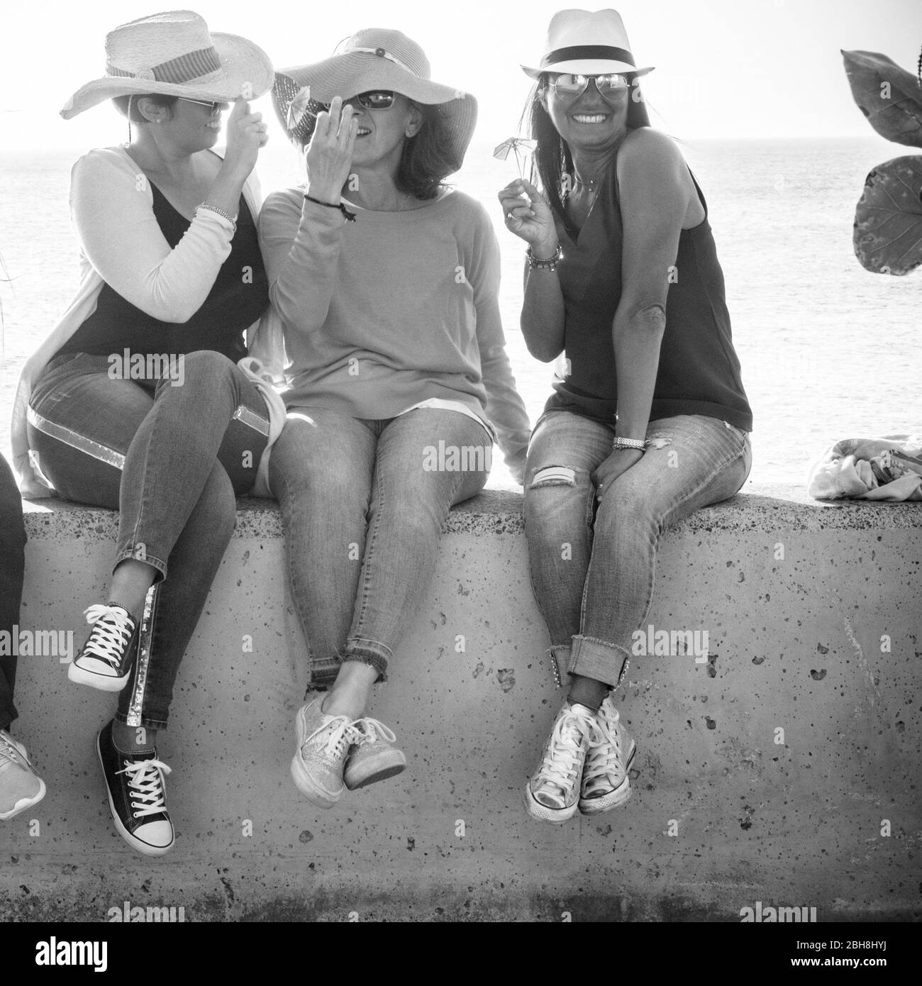 Black and white summer concept image with three middle age young woman laughing and enjoying together the friendship and the outdoor lifestyle - vacation and cheerful people Stock Photo