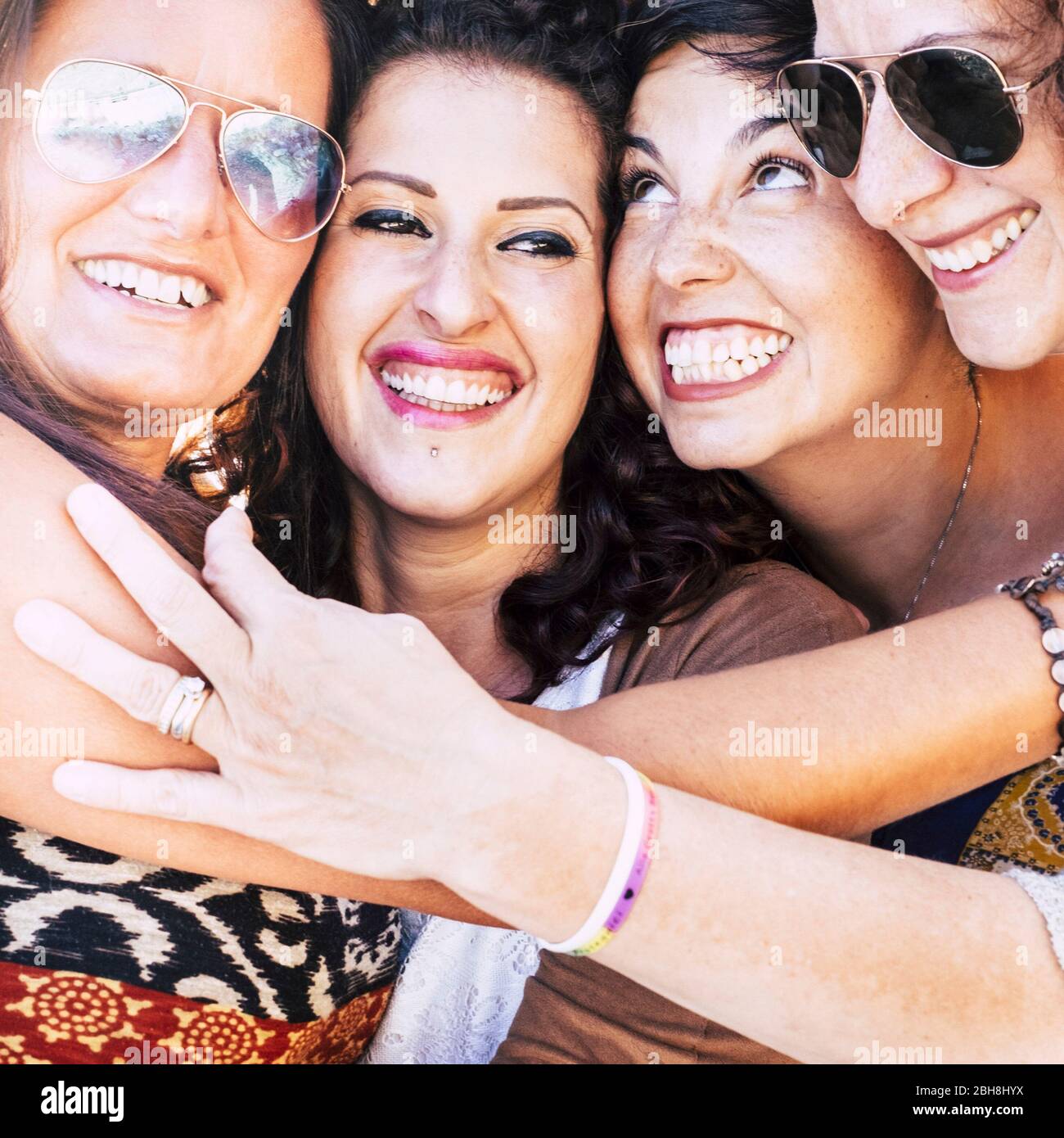 Portrait closeup with four young caucaisn awoman with faces united having a lot of fun together lauching and smiling like crazy - friendship and happiness people concept outdoor - cheerful females hugging eachother Stock Photo