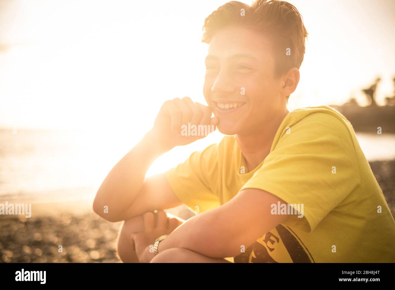 blonde and beautiful teenager 14 years old with sunflare and sunset in the background in Tenerife Canary Islands. young model enjoy the freedom and the beach Stock Photo