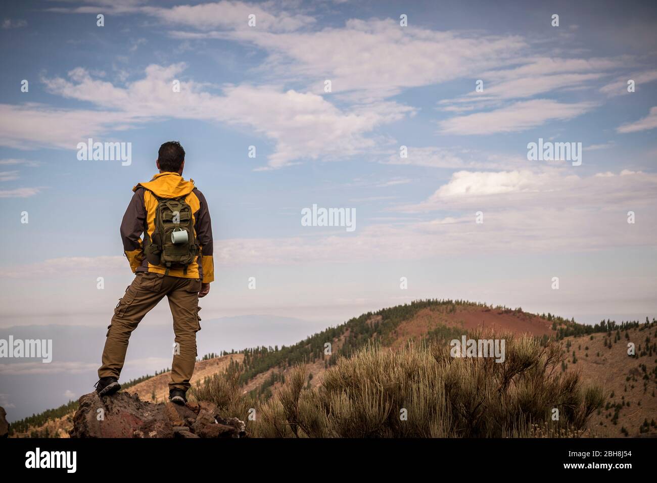 Lonely man in trekking adventure discover activity at the mountain with backpack - hiker looking the landscape and anjoying the wild undiscovered nature - beautiful environment for alternative vacation Stock Photo