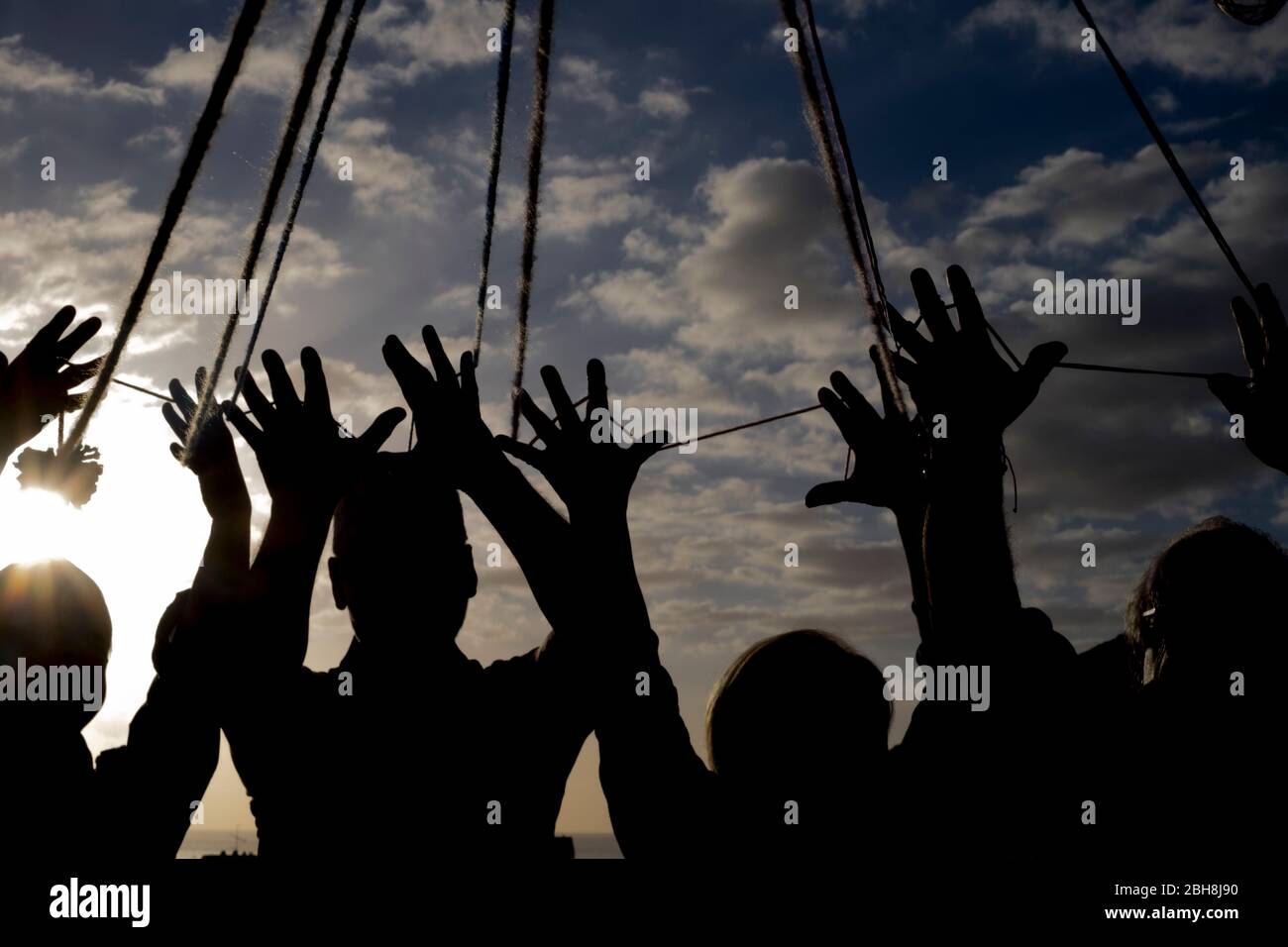group of hands in silhouette with cords to put them together united for friendship and cooperation concept - dark images with team people Stock Photo
