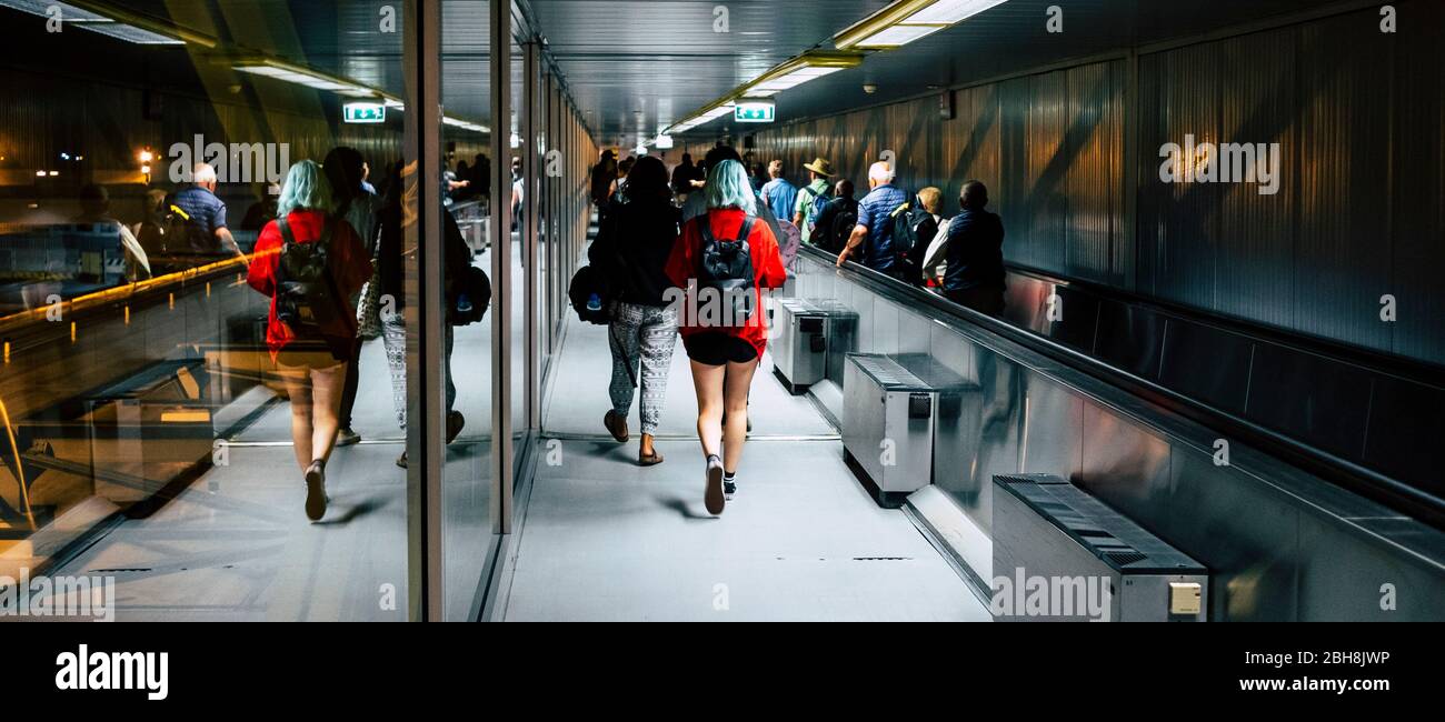 Crowd of men and women inside the airport gate moving to start or just arrived. People walking with hand bag and luggages and trolley with wheels. Travelers around the world concept Stock Photo