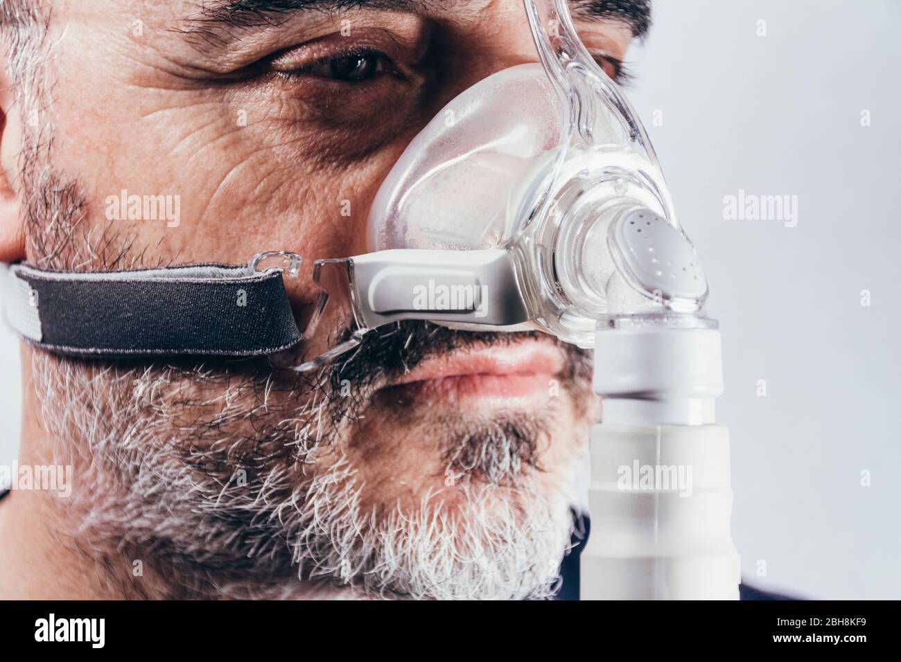 Senior man with respiratory mask for sleep disorders. Apnea. Medical devices. Air pump. Assisted breathing Stock Photo