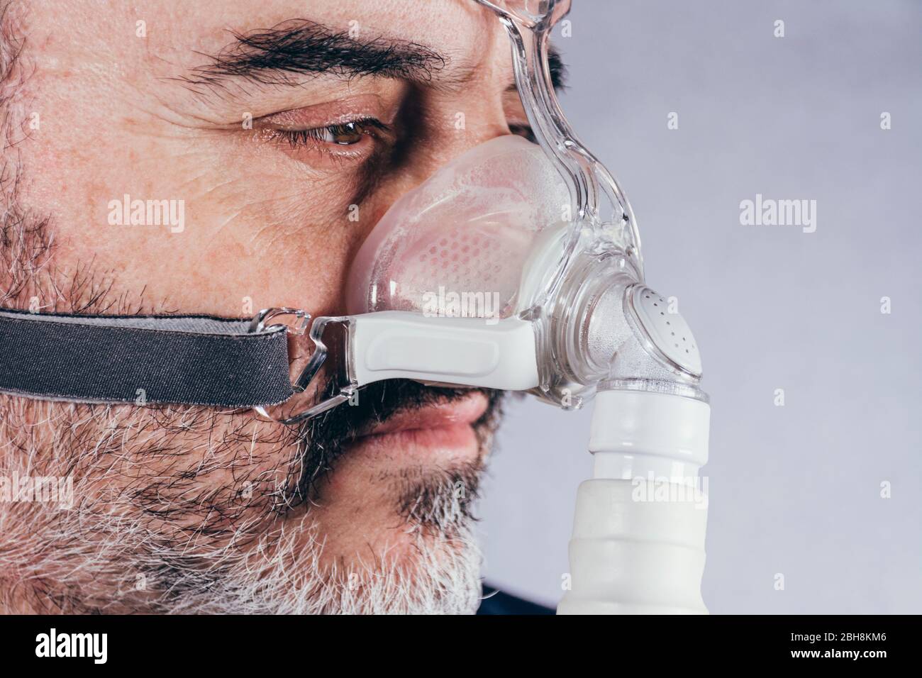 Senior man with respiratory mask for sleep disorders. Apnea. Medical devices. Air pump. Assisted breathing Stock Photo