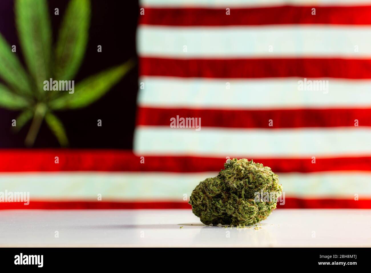 Cannabis flower nugget on a table in front of an American flag with a Marijuana pot leaf. Stock Photo