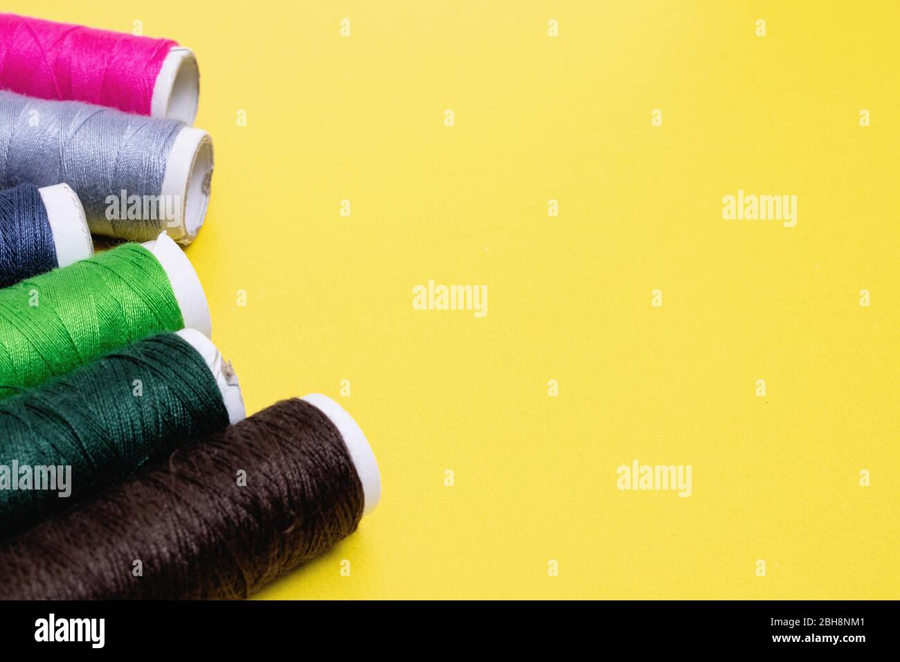 Coils with multicolored threads on yellow background Stock Photo