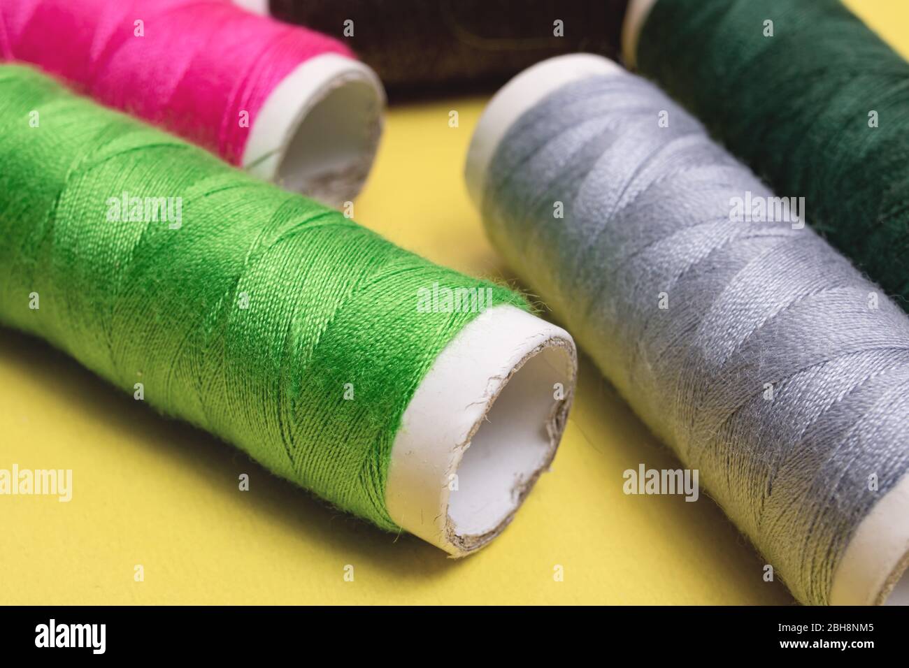 Coils with multicolored threads on yellow background Stock Photo