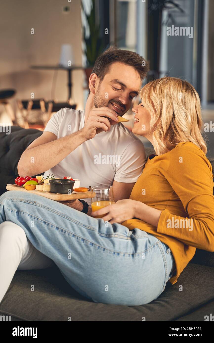 Happy married people eating together on the sofa Stock Photo