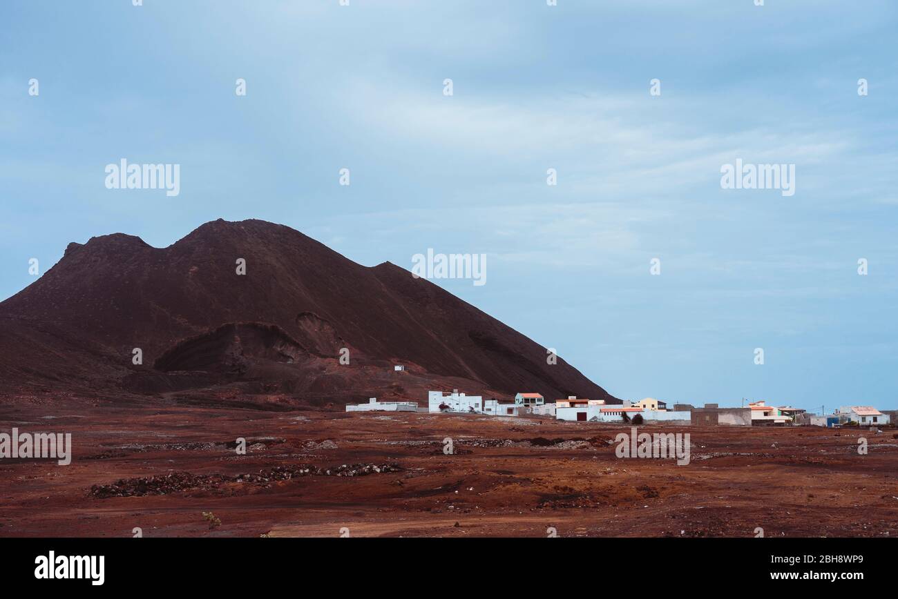 Local village Calhau at the foot of the volcanic crater. Single martian like dry red rock stand out from barren desert ground. Cape Verde - Sao Vicente Island. Stock Photo